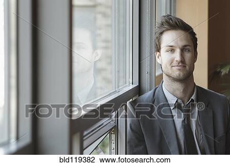 Stock Image - Businessman standing at window. Fotosearch