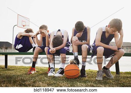 Stock Photo - Caucasian basketball team sulking by court. Fotosearch