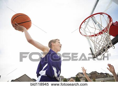 Caucasian boy dunking basketball in hoop View Large Photo Image Stock Photography - Caucasian boy dunking basketball in hoop. Fotosearch