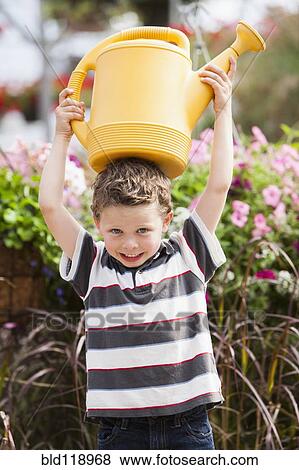Stock Photo - Caucasian boy playing with watering can. Fotosearch