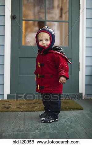 Stock Photo - Caucasian boy wearing winter coat on porch. Fotosearch