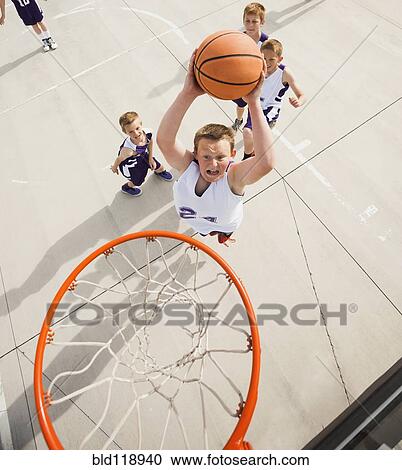 Stock Image - Caucasian boys playing basketball on court. Fotosearch