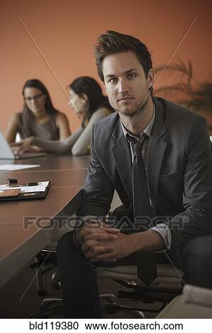 Stock Image - Caucasian businessman sitting at meeting table. Fotosearch