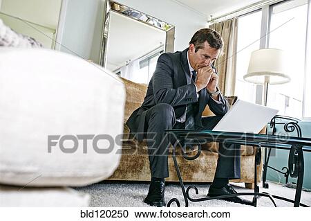 Stock Image - Caucasian businessman using laptop in living room. Fotosearch