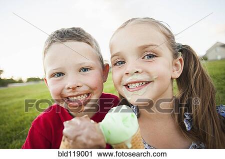 Stock Image - Caucasian children eating ice cream outdoors. Fotosearch