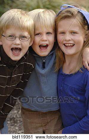 Stock Image - Caucasian children hugging outdoors. Fotosearch