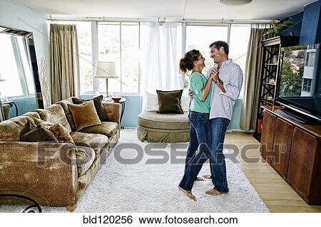 Stock Photograph - Caucasian couple dancing in living room. Fotosearch