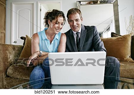 Caucasian couple using laptop in living room View Large Photo Image Stock Image - Caucasian couple using laptop in living room. Fotosearch
