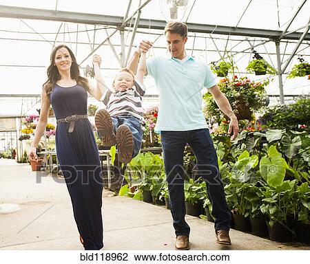 Stock Image - Caucasian family shopping in plant nursery. Fotosearch