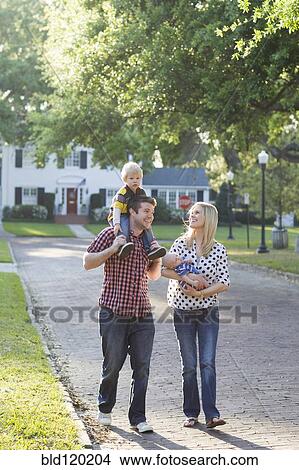 Caucasian family walking along neighborhood street View Large Photo Image Picture - Caucasian family walking along neighborhood street. Fotosearch