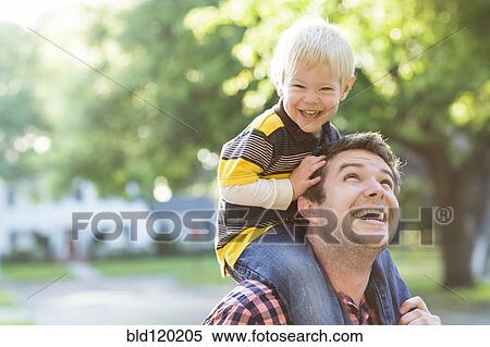 Stock Photography - Caucasian father carrying son on shoulders. Fotosearch