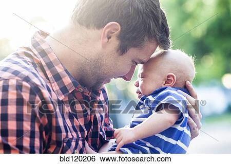 Stock Photograph - Caucasian father holding baby outdoors. Fotosearch