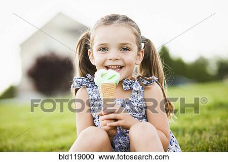 Stock Image - Caucasian girl eating ice cream outdoors. Fotosearch