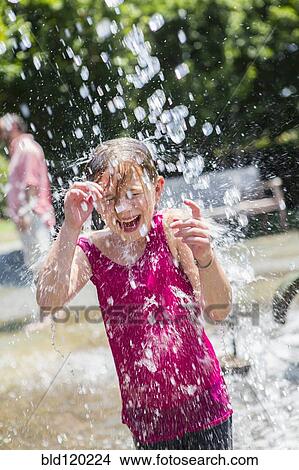 Picture - Caucasian girl playing in fountain. Fotosearch