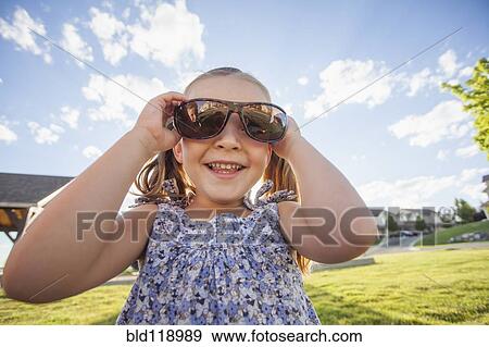 Stock Photo - Caucasian girl wearing sunglasses outdoors. Fotosearch
