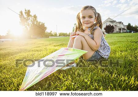 Stock Photo - Caucasian girl with kite in grass. Fotosearch