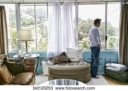 Stock Image - Caucasian man looking out window. Fotosearch