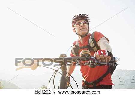 Stock Photo - Caucasian man pushing mountain bike. Fotosearch