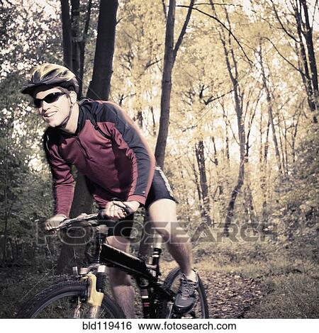 Stock Photograph - Caucasian man riding mountain bike in forest. Fotosearch