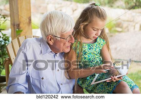 Stock Image - Caucasian man using digital tablet with granddaughter. Fotosearch