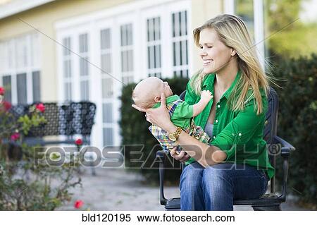 Stock Photography - Caucasian mother holding baby in garden. Fotosearch