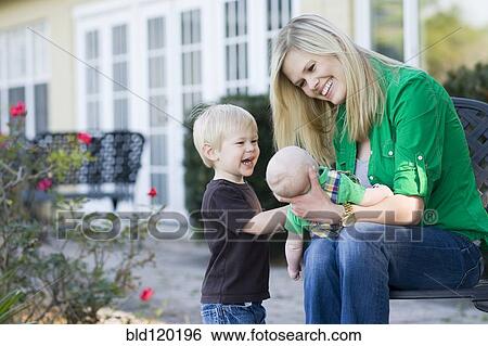 Stock Photograph - Caucasian mother relaxing with children in garden. Fotosearch
