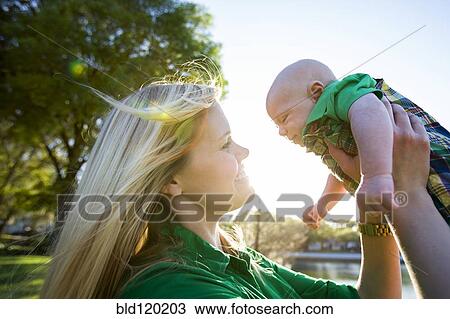 Stock Image - Caucasian woman holding baby outdoors. Fotosearch