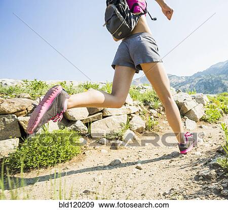 Stock Photo - Caucasian woman running on rocky trail. Fotosearch
