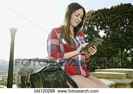 Caucasian woman using digital tablet outdoors View Large Photo Image Stock Photo - Caucasian woman using digital tablet outdoors. Fotosearch