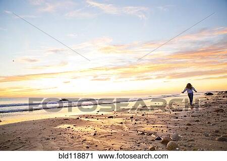 Stock Image - Caucasian woman walking on beach. Fotosearch
