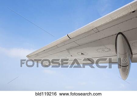 Stock Photograph - Close up of airplane wing against blue sky. Fotosearch