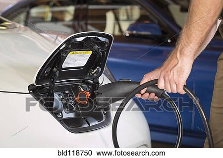 Close up of Caucasian man recharging electric car View Large Photo Image Stock Image - Close up of Caucasian man recharging electric car. Fotosearch