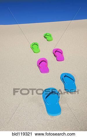Stock Image - Colorful flip flops on sand. Fotosearch
