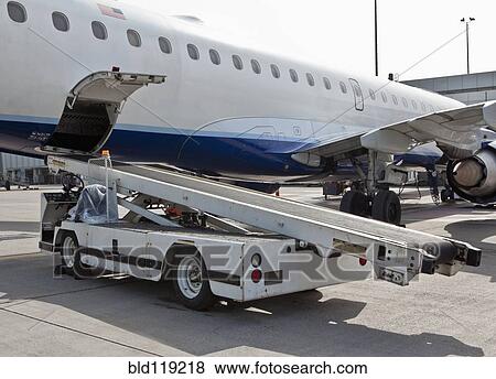 Stock Photo - Conveyor belt at airplane cargo hold on runway. Fotosearch