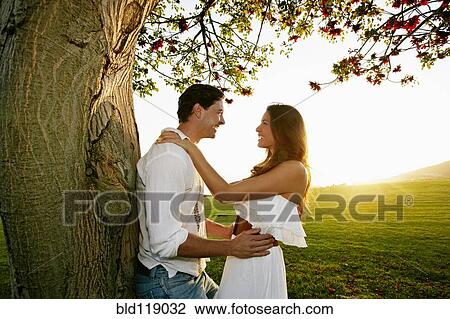 Couple hugging by tree in park View Large Photo Image Stock Image - Couple hugging by tree in park. Fotosearch