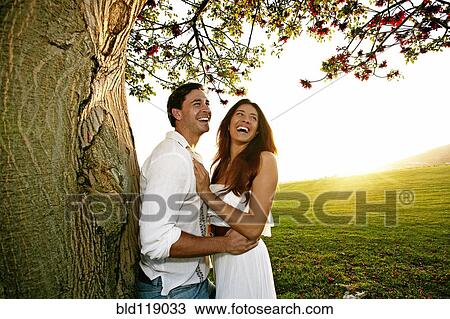 Couple hugging by tree in park View Large Photo Image Stock Image - Couple hugging by tree in park. Fotosearch
