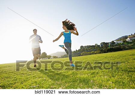Stock Image - Couple running together in park. Fotosearch