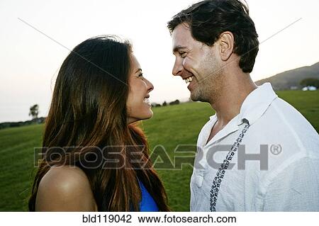 Stock Image - Couple smiling together in park. Fotosearch