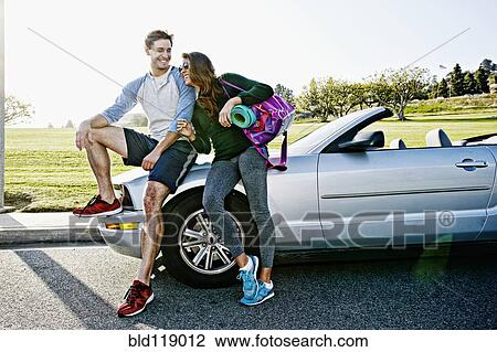 Stock Image - Couple wearing workout gear by convertible. Fotosearch
