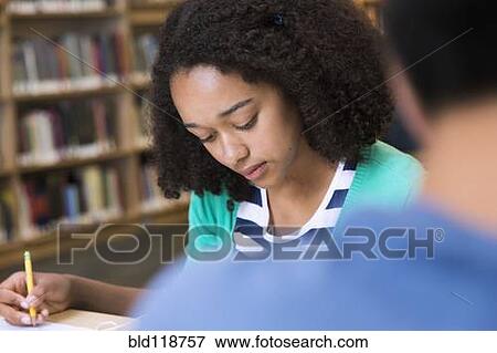 Stock Photo - Female student taking notes in library. Fotosearch