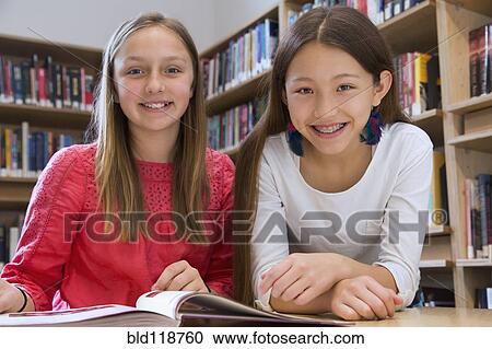 Stock Image - Female students smiling in library. Fotosearch