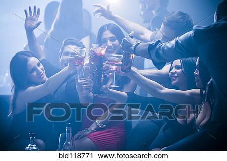 Stock Image - Friends toasting each other in nightclub. Fotosearch
