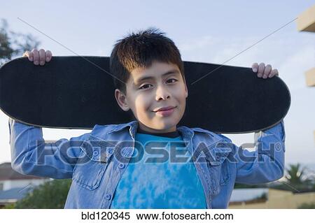 Stock Photography - Hispanic boy carrying skateboard. Fotosearch