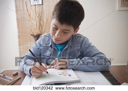 Stock Image - Hispanic boy doing homework at desk. Fotosearch