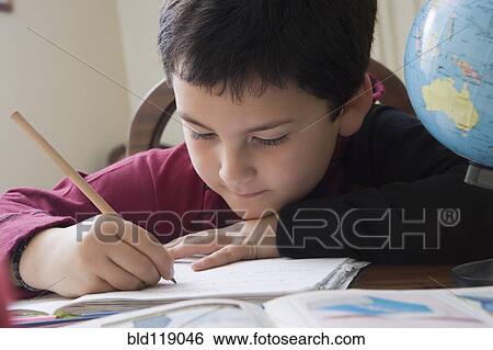 Stock Photograph - Hispanic boy doing homework at table. Fotosearch