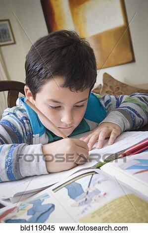 Stock Photography - Hispanic boy doing homework at table. Fotosearch