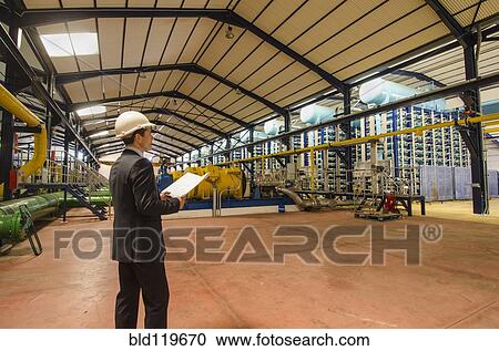Stock Image - Hispanic businessman checking machinery. Fotosearch