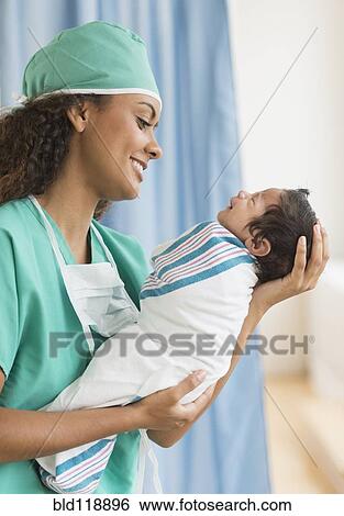 Hispanic doctor holding newborn in hospital View Large Photo Image Stock Photograph - Hispanic doctor holding newborn in hospital. Fotosearch