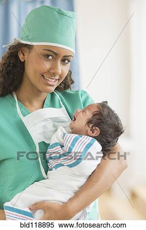 Stock Photography - Hispanic doctor holding newborn in hospital. Fotosearch