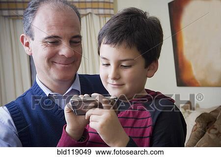 Stock Photo - Hispanic father and son using cell phone. Fotosearch